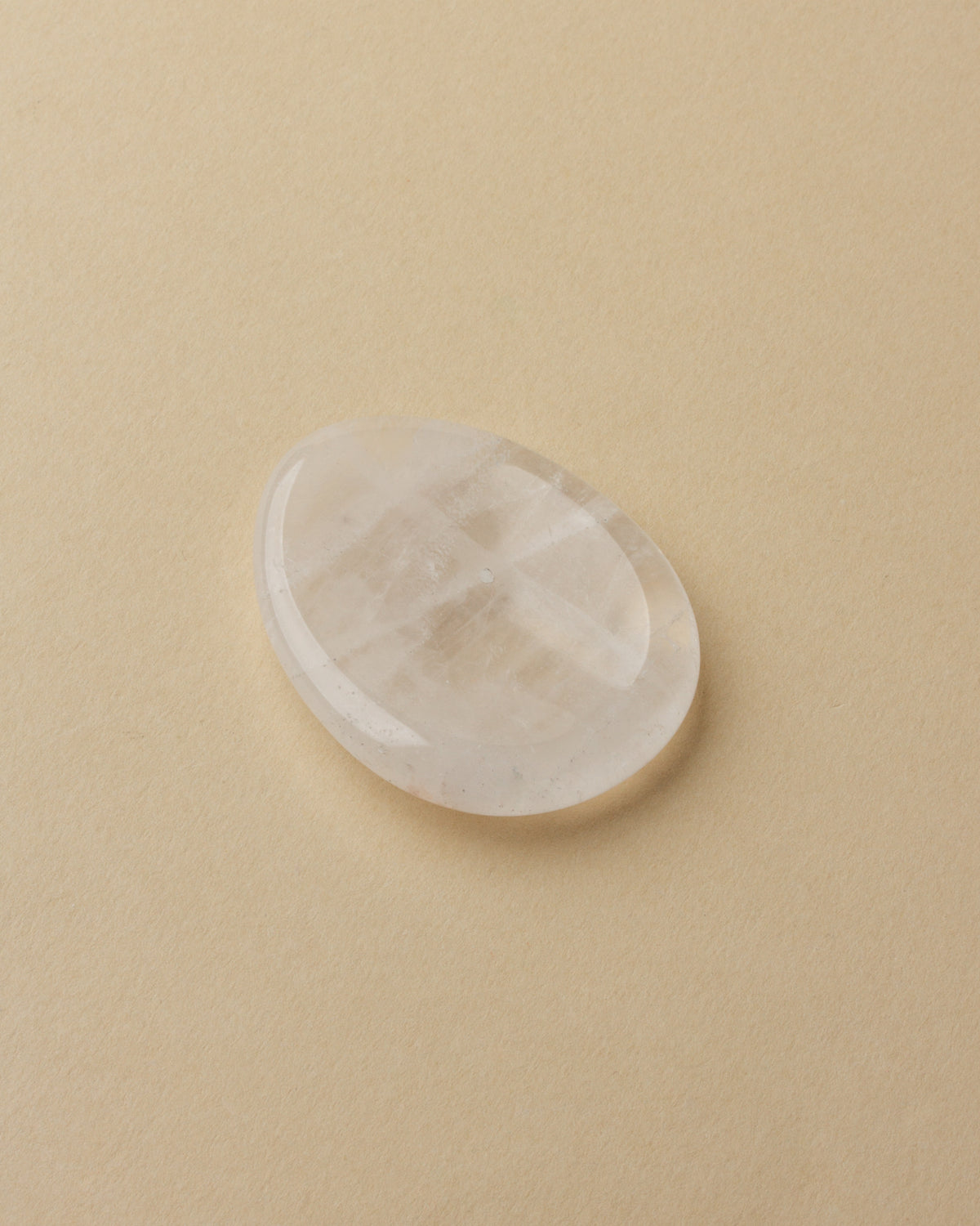 A smooth quartz stone with a slight indent, placed on a white surface.