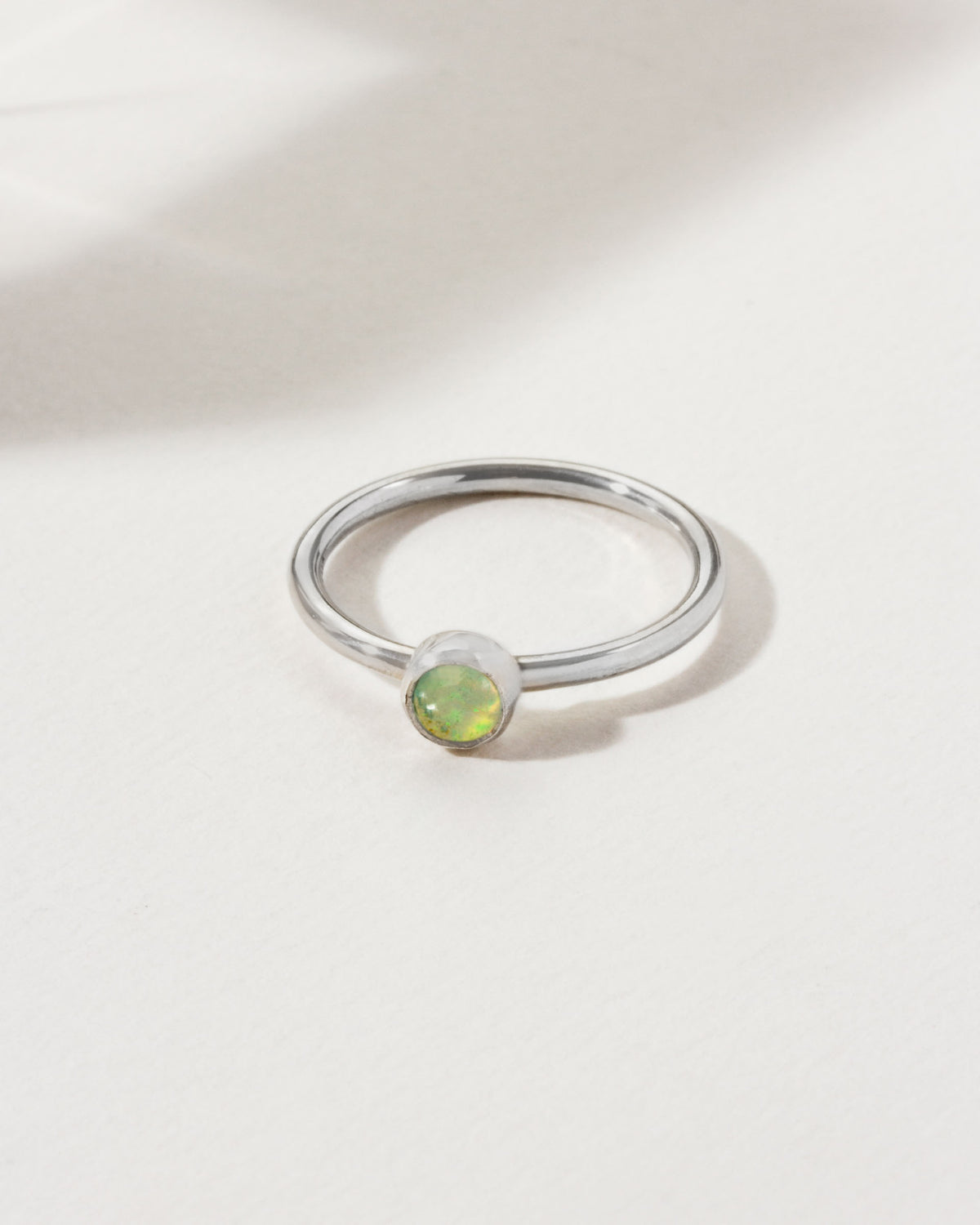 Sterling silver ring with a round, light-green opal gemstone.