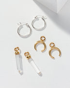Silver hoops, gold crescent charms, and clear quartz points with gold caps, all scattered
