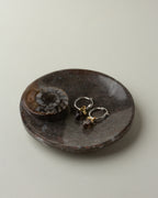 Brown Journey of Life catchall with earrings inside, sitting on a white surface.