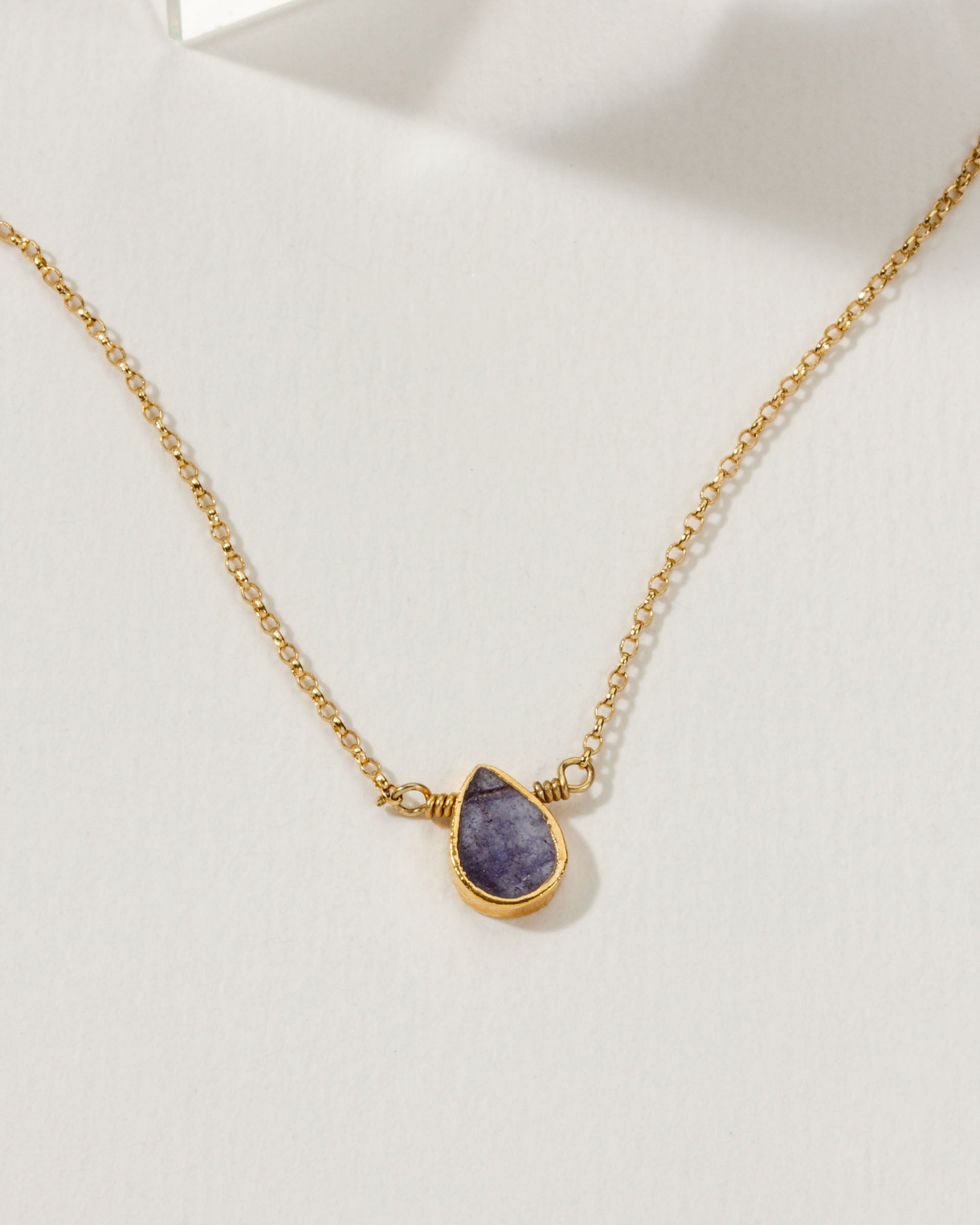 Gold necklace with a teardrop-shaped Tanzanite gemstone pendant.
