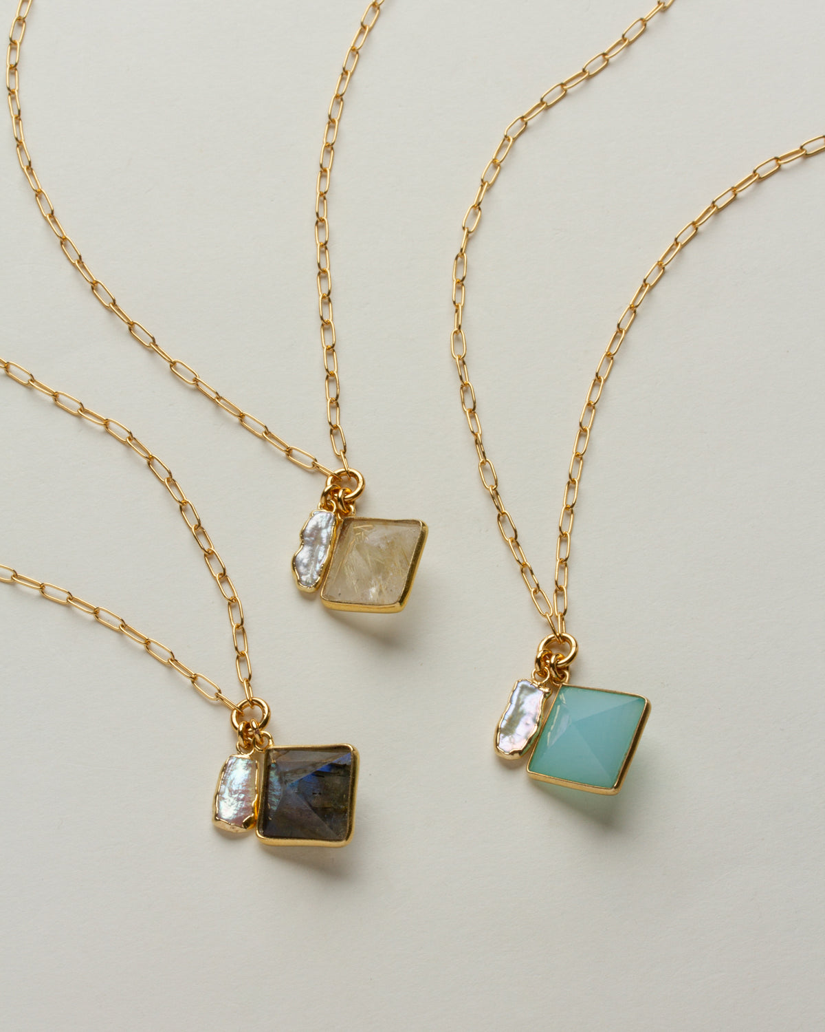 Three Sea and Stone gold necklaces with labradorite, rutilated quartz, and blue gemstone pendants