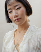 Model wearing Sea and Stone necklace with rutilated quartz pendant and matching earrings