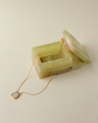 Green Calcite jewelry box with gold necklace draped on the front.