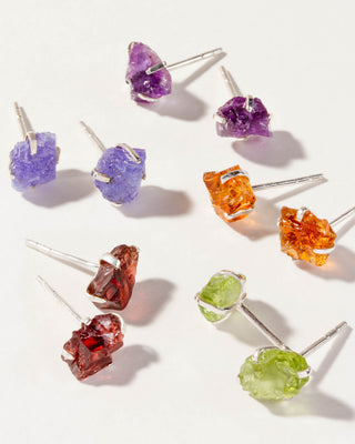 A collection of Sterling Raw Beauty post earrings with various colorful gemstones, each representing different birth months.