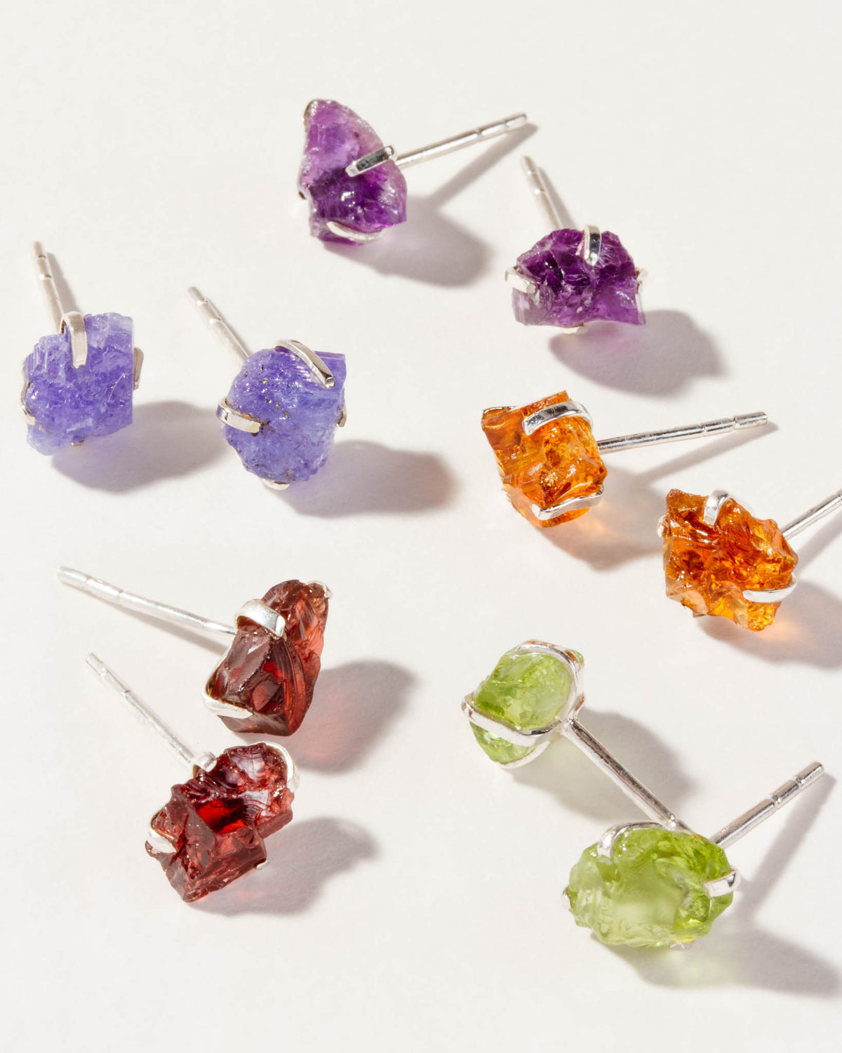 Collection of Sterling Raw Beauty post earrings with gems, each representing different birth months.