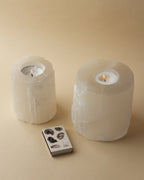 Two lit Tranquility Candle Holders sit next to a matchbox with images of minerals.
