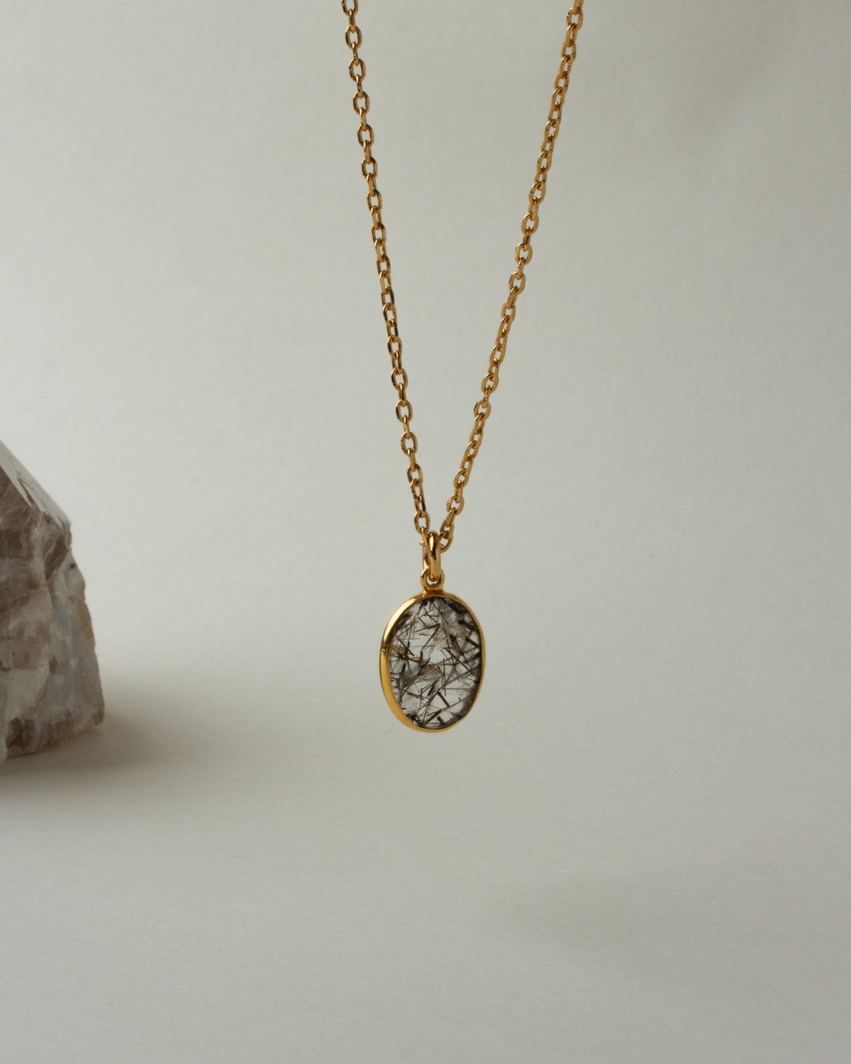 Gold chain necklace featuring tourmalinated quartz pendant.